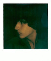 a polaroid photo of a young man with dark hair